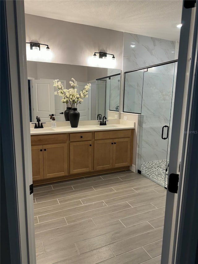 bathroom with a textured ceiling, vanity, and an enclosed shower