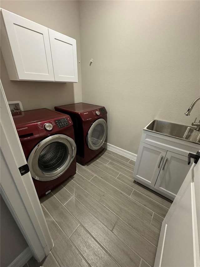 clothes washing area with cabinets, independent washer and dryer, and sink