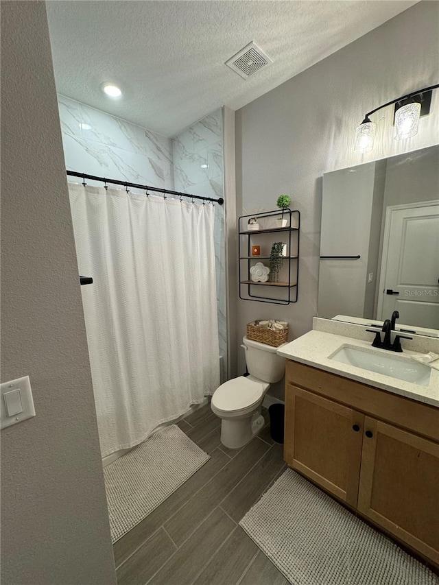 bathroom featuring vanity, a textured ceiling, and toilet