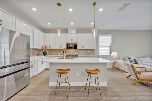 1554 Outback Rd W, Saint Cloud, FL 34771 - kitchen featuring freestanding refrigerator, open floor plan, tasteful backsplash, a center island with sink, and light countertops