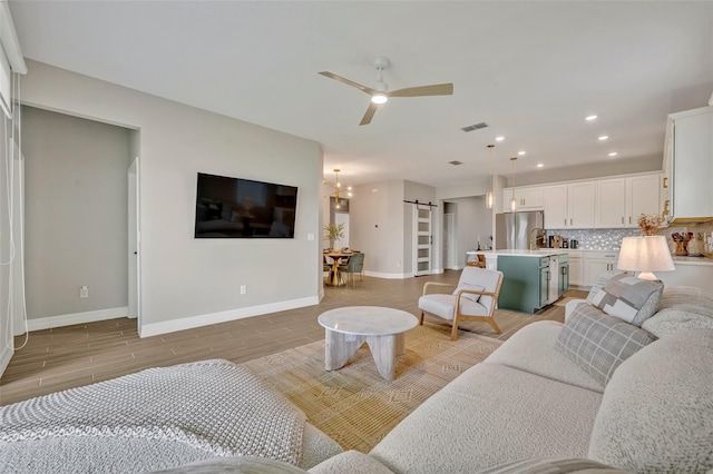 1554 Outback Rd W, Saint Cloud, FL 34771 - living area with a ceiling fan, recessed lighting, a barn door, and light wood finished floors