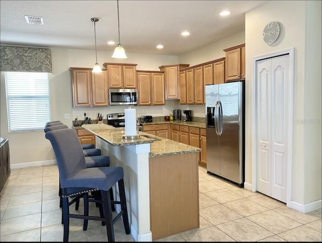 kitchen featuring a center island, light stone counters, a kitchen breakfast bar, pendant lighting, and appliances with stainless steel finishes