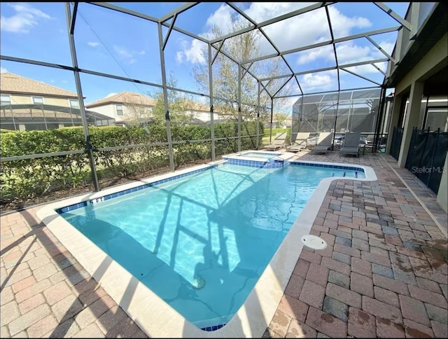 view of pool featuring an in ground hot tub, glass enclosure, and a patio area