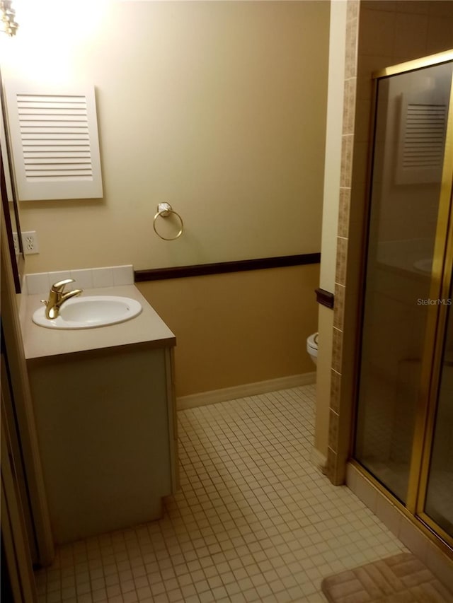 bathroom with tile patterned flooring, vanity, toilet, and a shower with shower door