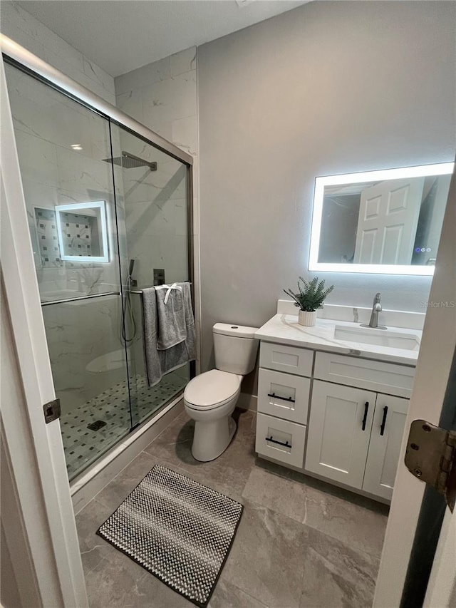 bathroom with vanity, toilet, and a shower with door