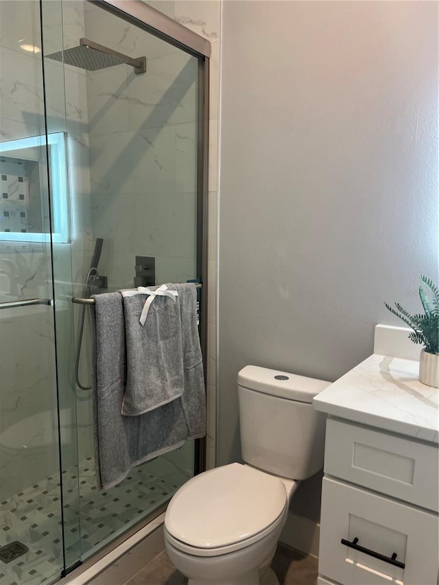 bathroom featuring vanity, toilet, and a shower with shower door