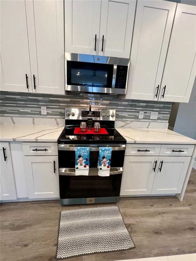 kitchen featuring white cabinets, decorative backsplash, stainless steel appliances, and light hardwood / wood-style floors