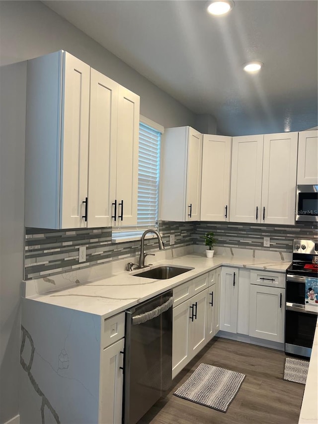 kitchen featuring white cabinets, sink, decorative backsplash, dark hardwood / wood-style flooring, and stainless steel appliances