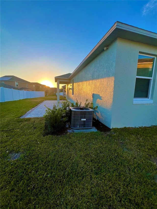 yard at dusk featuring central AC unit