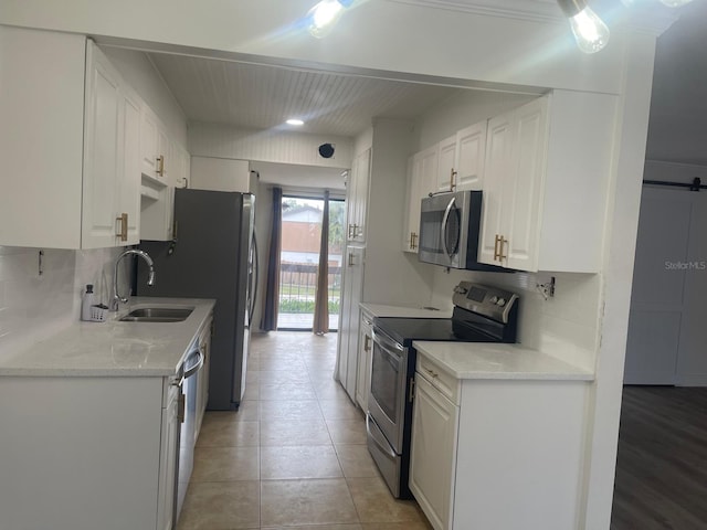 kitchen with backsplash, white cabinetry, sink, and stainless steel appliances