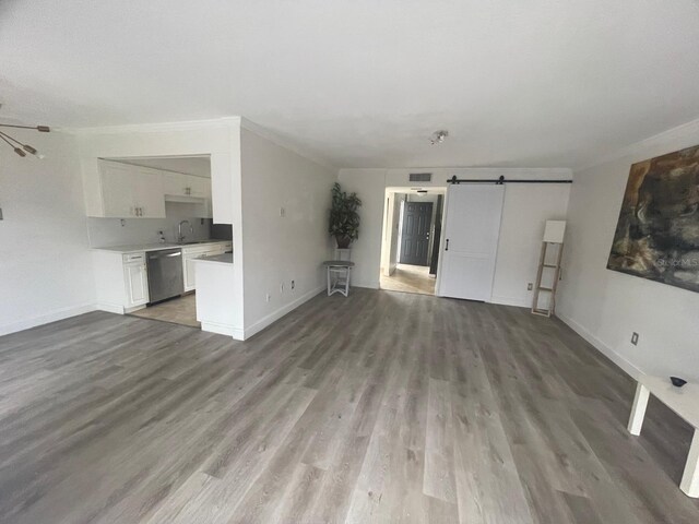 unfurnished living room with a barn door and wood-type flooring