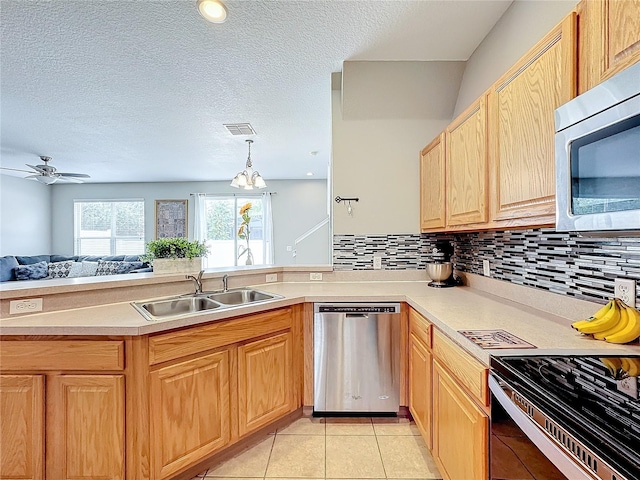 kitchen with a peninsula, a sink, visible vents, open floor plan, and appliances with stainless steel finishes