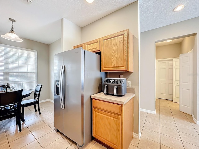 kitchen featuring baseboards, light tile patterned flooring, light countertops, and stainless steel fridge with ice dispenser