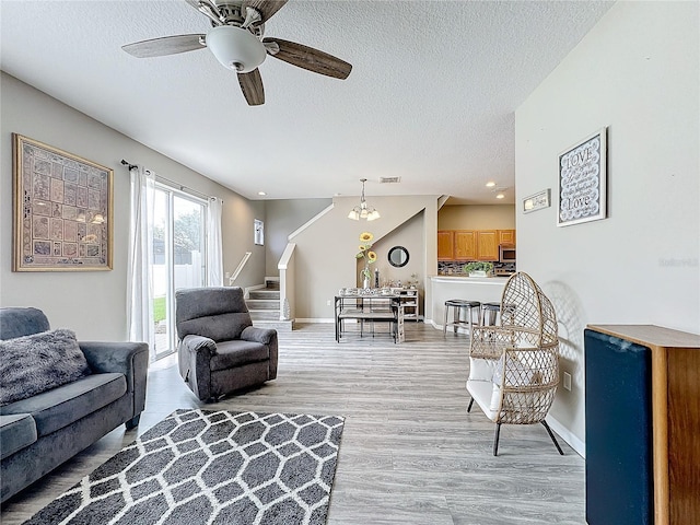 living area with baseboards, a ceiling fan, stairway, wood finished floors, and a textured ceiling