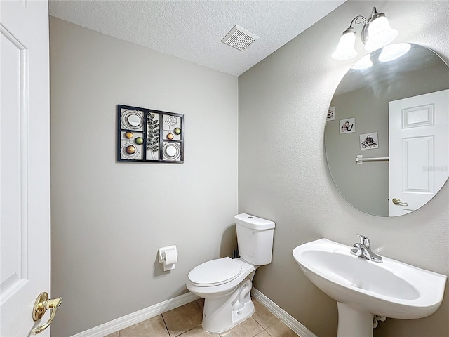 bathroom featuring visible vents, toilet, tile patterned flooring, a textured ceiling, and a sink