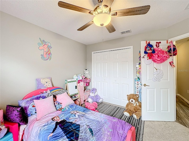 bedroom featuring ceiling fan, a textured ceiling, visible vents, and a closet