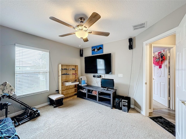 workout area featuring a textured ceiling, ceiling fan, carpet flooring, and visible vents