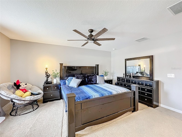 bedroom featuring light colored carpet, visible vents, ceiling fan, and a textured ceiling