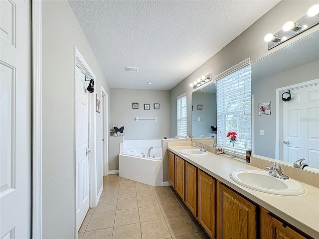 full bathroom with a bath, double vanity, a sink, and tile patterned floors