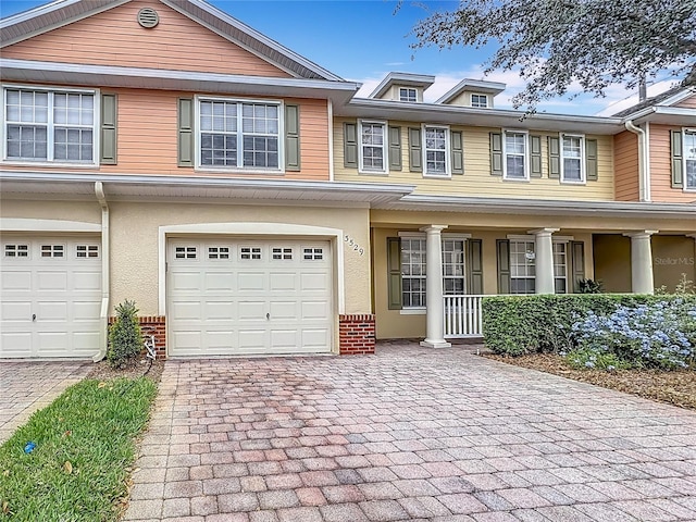 view of property with a garage, stucco siding, decorative driveway, and brick siding