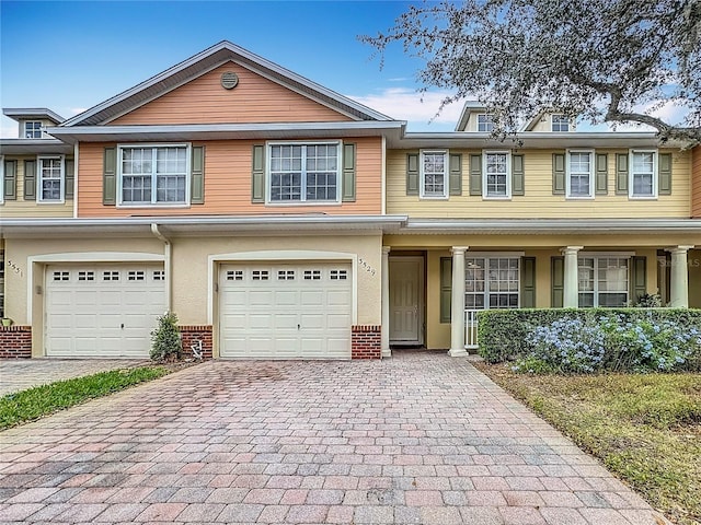 multi unit property featuring a garage, decorative driveway, and brick siding