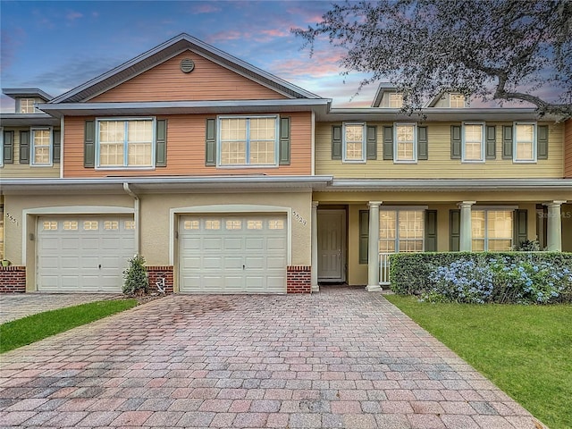 townhome / multi-family property featuring a garage, decorative driveway, brick siding, and stucco siding