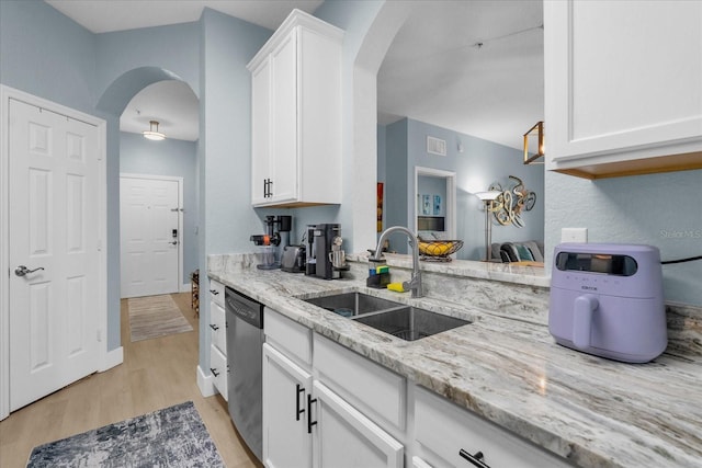 kitchen with sink, light hardwood / wood-style flooring, stainless steel dishwasher, and white cabinets