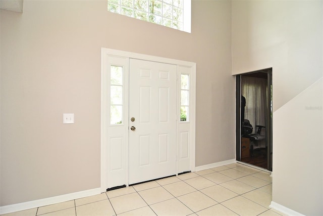 entrance foyer featuring a towering ceiling, light tile patterned floors, and plenty of natural light