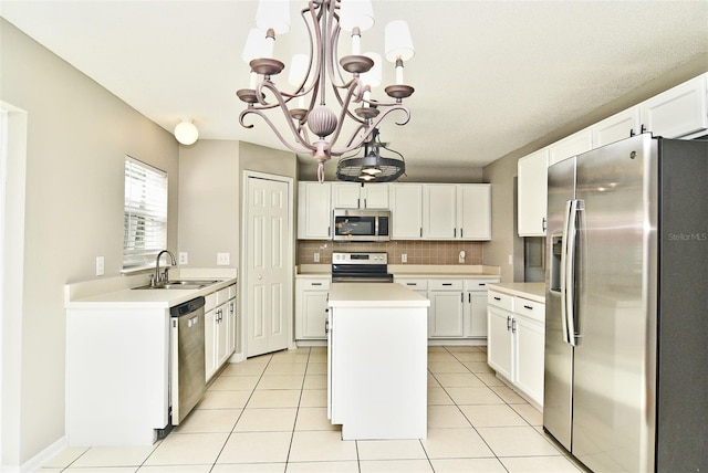 kitchen with stainless steel appliances, a center island, sink, white cabinetry, and decorative light fixtures