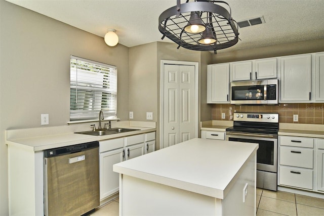 kitchen with a center island, white cabinets, sink, light tile patterned flooring, and appliances with stainless steel finishes