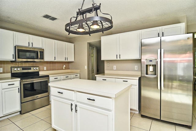 kitchen featuring appliances with stainless steel finishes, decorative light fixtures, backsplash, a kitchen island, and white cabinets