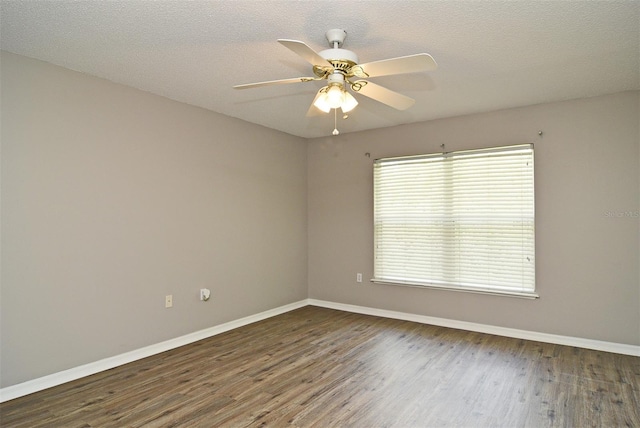 spare room featuring dark wood-type flooring, a textured ceiling, and ceiling fan