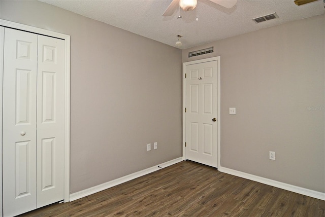 unfurnished bedroom featuring a closet, a textured ceiling, ceiling fan, and dark hardwood / wood-style floors