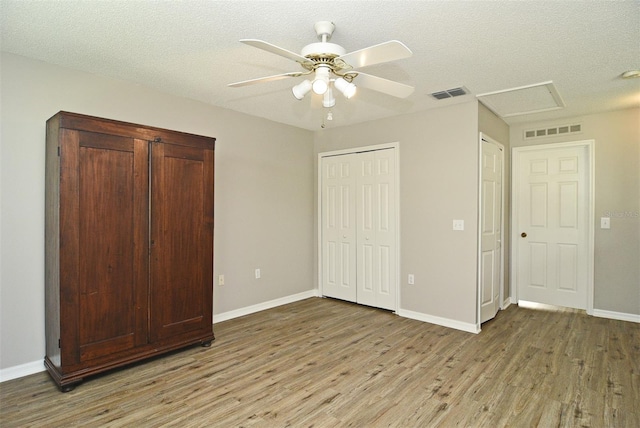 unfurnished bedroom featuring light hardwood / wood-style floors, ceiling fan, and a textured ceiling