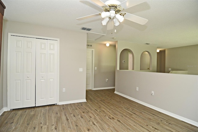 unfurnished bedroom with light hardwood / wood-style floors, ceiling fan, a textured ceiling, and a closet