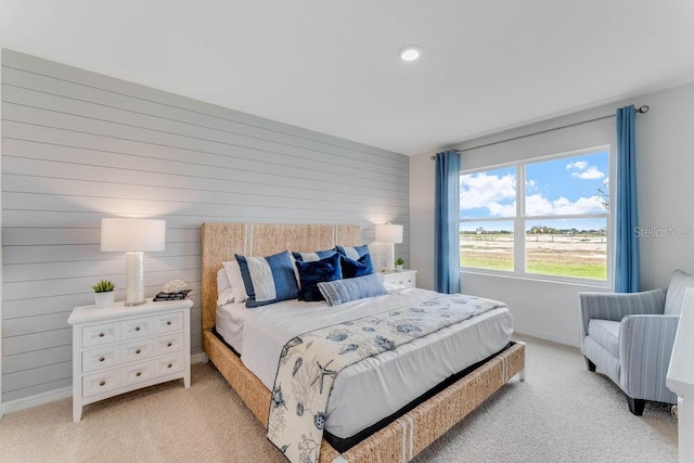 bedroom featuring wooden walls and light carpet