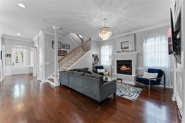 living room featuring dark hardwood / wood-style flooring, decorative columns, a chandelier, and crown molding