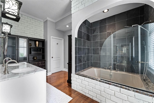 bathroom with crown molding, vanity, a textured ceiling, tiled shower / bath combo, and hardwood / wood-style flooring