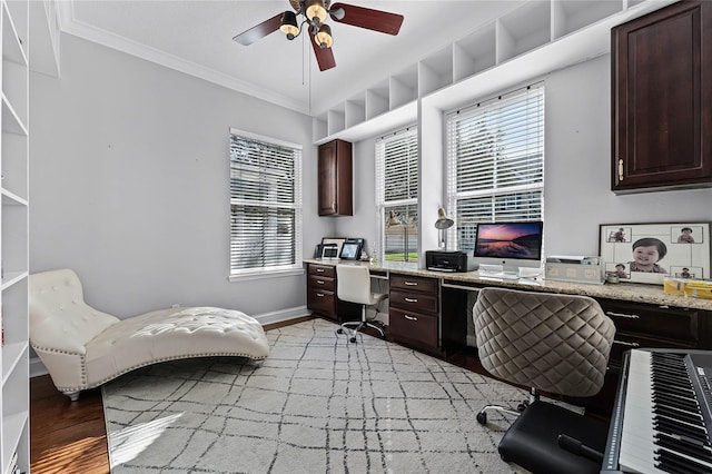 office with light wood-type flooring, built in desk, ceiling fan, and crown molding