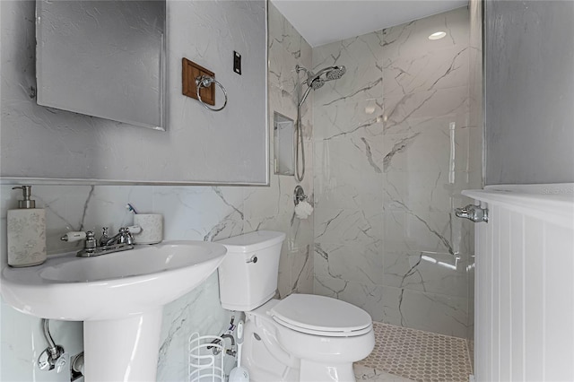 bathroom with toilet, a tile shower, and tile walls