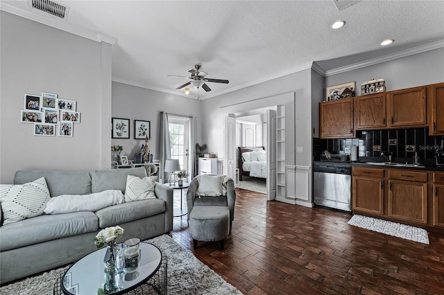 living room with dark wood-type flooring, a textured ceiling, sink, ceiling fan, and crown molding