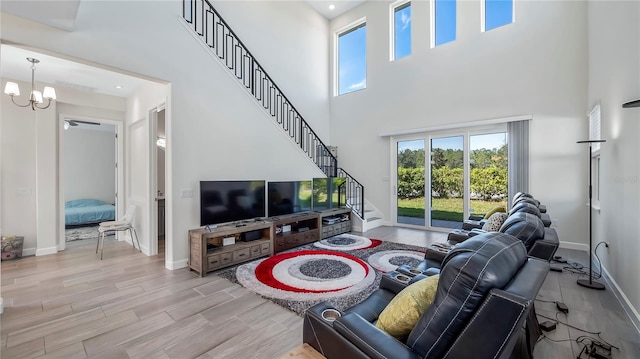 living room with a chandelier, light hardwood / wood-style floors, and a towering ceiling