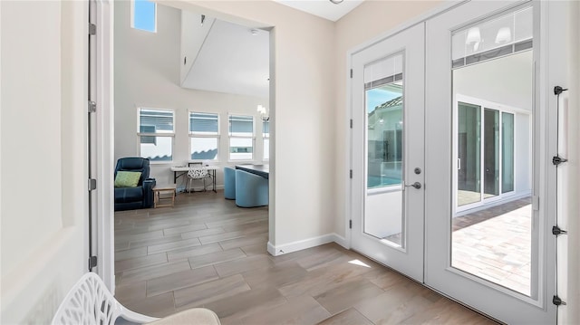 entryway with french doors, a wealth of natural light, an inviting chandelier, and light hardwood / wood-style flooring