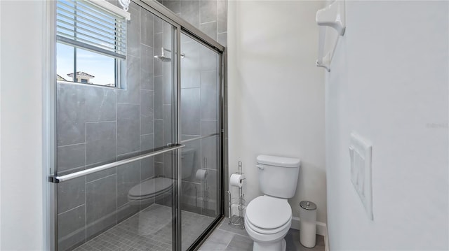 bathroom with a shower with door, tile patterned flooring, and toilet