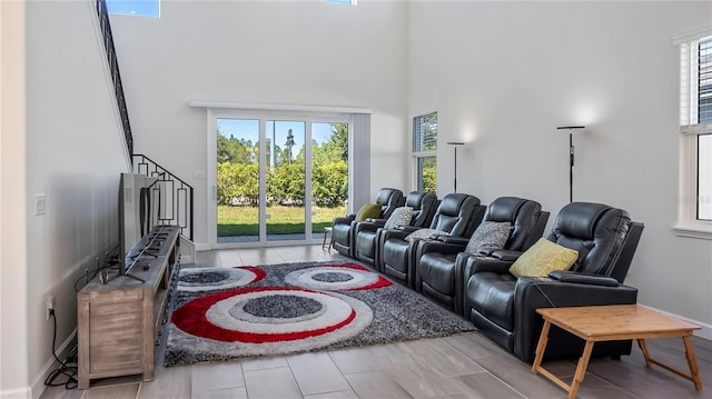 home theater room featuring light hardwood / wood-style flooring, a healthy amount of sunlight, and a towering ceiling