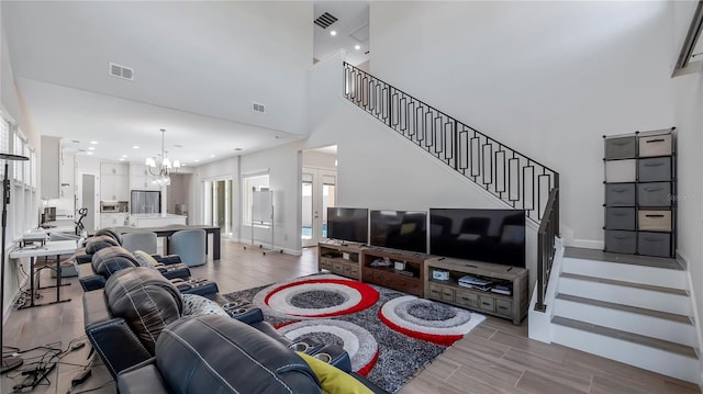 living room featuring light hardwood / wood-style floors, a chandelier, and a high ceiling