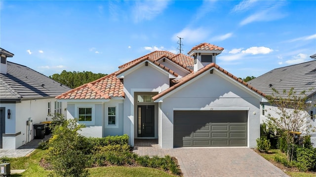 mediterranean / spanish-style house with a tiled roof, a garage, driveway, and stucco siding