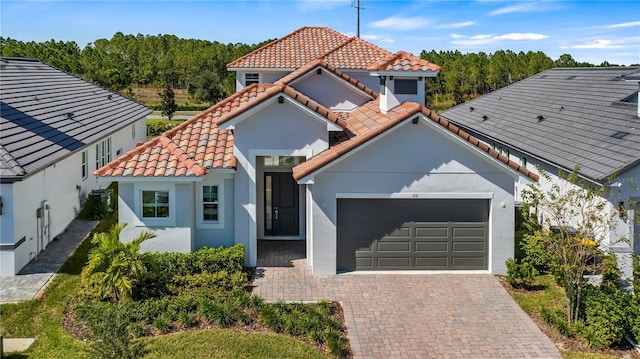 mediterranean / spanish house with stucco siding, a garage, driveway, and a tile roof