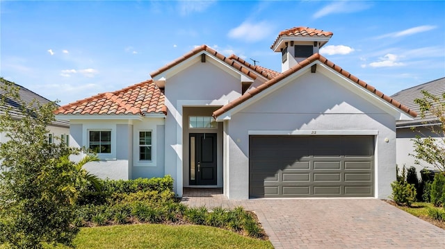 mediterranean / spanish-style home with stucco siding, a tiled roof, driveway, and a garage