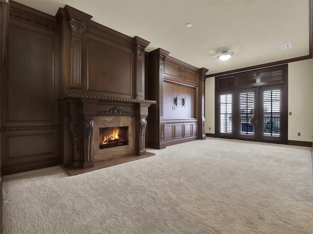 unfurnished living room with baseboards, visible vents, a fireplace, ornamental molding, and light carpet